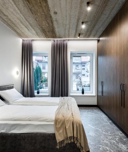 a bedroom with a large bed and two windows at Oldtown Trinity House in Kaunas