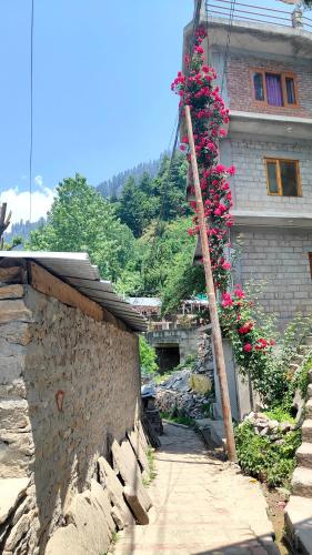 a building with a tree with pink flowers on it at Hotel Nirvana in Vashisht