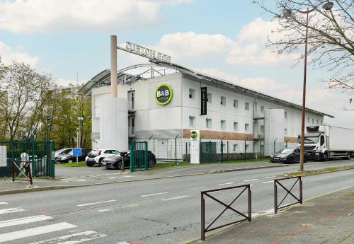 a building on a street with cars parked in a parking lot at B&B HOTEL Viry-Châtillon in Viry-Châtillon
