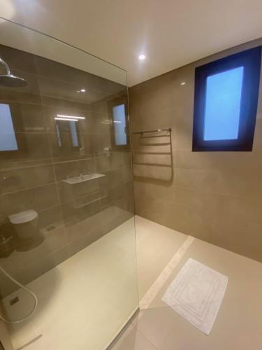 a bathroom with a glass shower with a blue window at Villa Rotana Tulip in Salalah