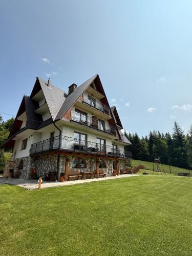a large building with a green lawn in front of it at Pokoje i apartament z widokiem na Tatry in Kościelisko