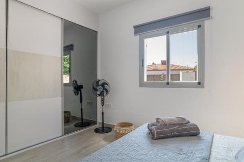 1 dormitorio con ventana, 1 cama y ventilador en Villa el Olivar 1, en Barbate