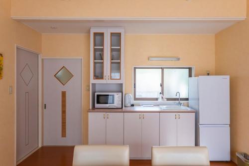 a kitchen with white cabinets and a white refrigerator at Le Nessa Jyogasaki in Ito