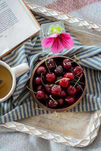 a bowl of cherries next to a book and a cup of tea at The Atelier Apartment in Kingsbridge