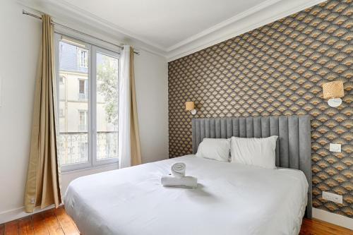 une chambre avec un grand lit blanc et une fenêtre dans l'établissement Montmartre Seveste II Beautiful 2BR Apartment, à Paris
