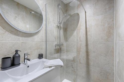 une salle de bain avec une douche, un lavabo et un miroir dans l'établissement Montmartre Seveste II Beautiful 2BR Apartment, à Paris