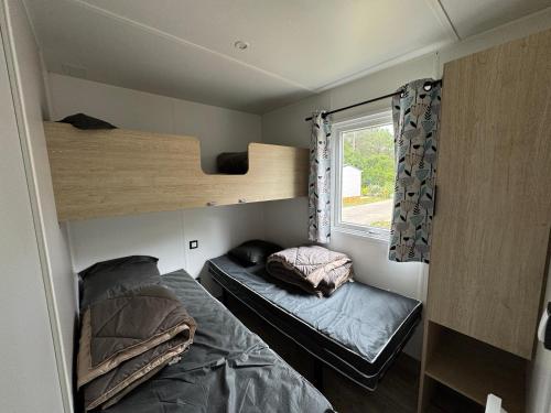 a small room with two bunk beds and a window at Bungalow Lodge 2 chambres in Lège-Cap-Ferret