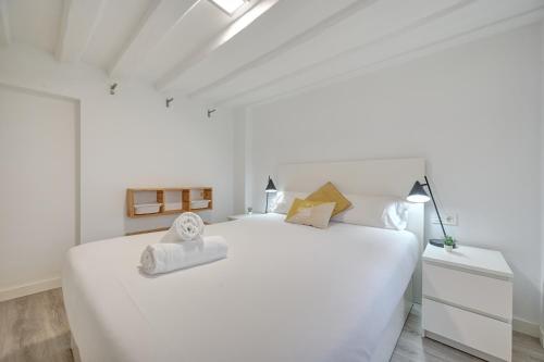 a white bedroom with a large white bed with towels on it at El Mirador de la Estafeta by Clabao in Pamplona