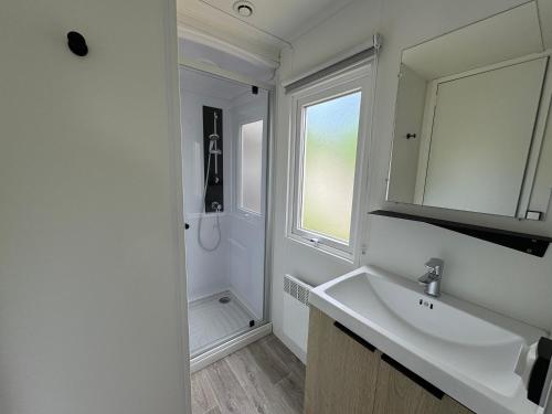 a white bathroom with a sink and a mirror at Bungalow Lodge 2 chambres in Lège-Cap-Ferret