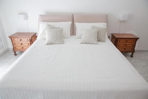 a large white bed with pillows and two tables at Tra il Vesuvio e il Mare Apartment in Torre del Greco