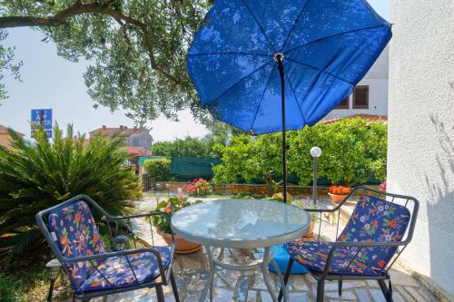 a table and chairs with a blue umbrella at Apartments Marta by Rent Istria in Novigrad Istria
