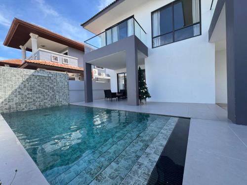 a house with a swimming pool in front of a house at Eakmongkol Luxury Five-Bedroom Pool Villa in Jomtien Beach
