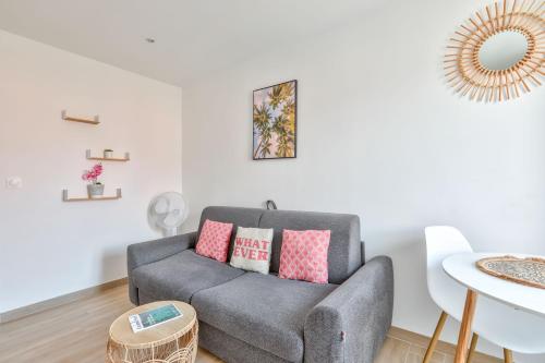 - un salon avec un canapé gris et des oreillers roses dans l'établissement Magnifique studio en plein centre de Nice, à Nice