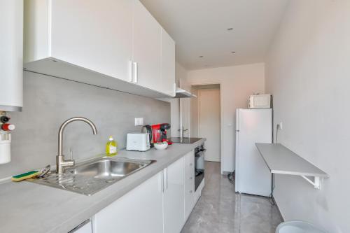 La cuisine blanche est équipée d'un évier et d'un réfrigérateur. dans l'établissement Magnifique studio en plein centre de Nice, à Nice