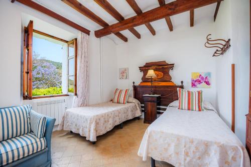 a room with two beds and a chair and a window at Cas Patró Lau Bis in Fornalutx