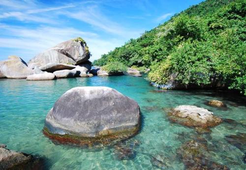 a large rock in the water next to a mountain at Canto de Paz Trindade Hospedagem in Trindade