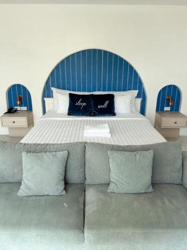 a bed with a blue headboard and a couch with pillows at Costa Beach Residence & Jacuzzi in Sattahip