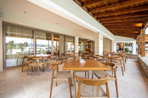 a restaurant with wooden tables and chairs and windows at Aegean Houses in Kos Town