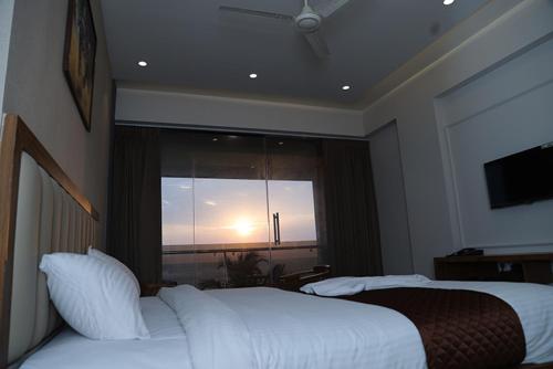 a bedroom with a large bed and a large window at Palm Breeze Beach Resort in Mangalore