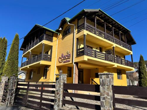 a yellow building with a fence in front of it at Casa Maria Azuga by Genco in Azuga