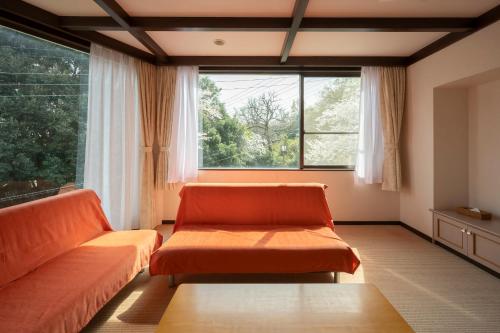 a living room with two orange couches and a large window at Le Nessa Jyogasaki in Ito