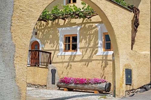 a building with an arch with flowers in front of it at Bertollhof Apfelerlebnis in Silandro