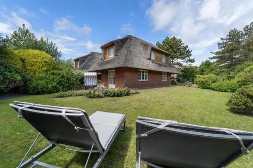 a house with a thatched roof and two lawn chairs at Avenarius Hüs in Kampen