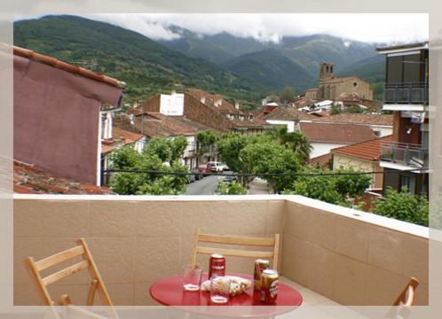 a table and chairs on a balcony with a view of a city at Apartamentos Hervasypunto in Hervás