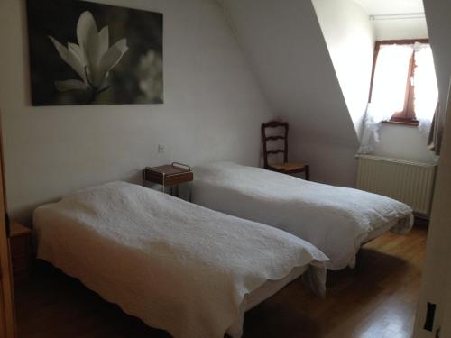 アンマーシュヴィアにあるGîte Sonnenbergの壁に絵画が飾られた部屋のベッド2台