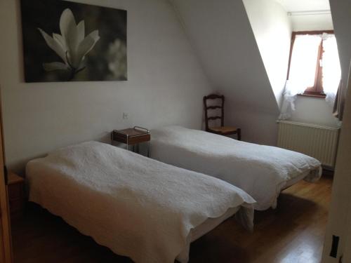 two beds in a room with a painting on the wall at Gîte Sonnenberg in Ammerschwihr