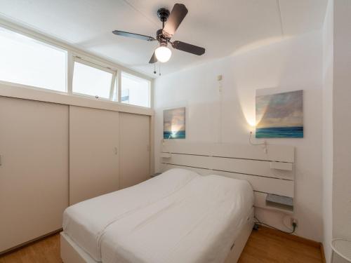 Un dormitorio blanco con una cama y un ventilador de techo. en Apartment in Julianadorp by the Sea, en Julianadorp