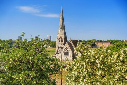 an old church with a steeple with trees in the foreground at The Clarendon Hotel in London