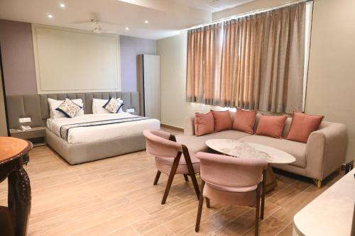 a hotel room with a bed and a couch and a table at Galaxy Triveni in Prayagraj