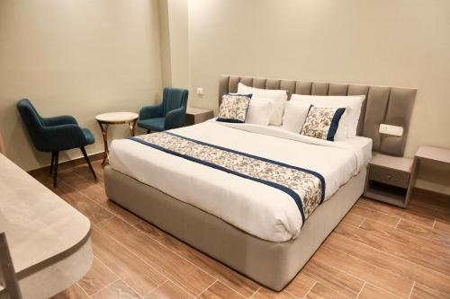 a bedroom with a large bed and two blue chairs at Galaxy Triveni in Prayagraj