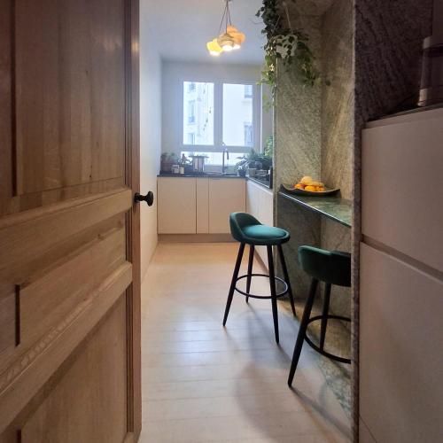 - une cuisine avec un comptoir et deux tabourets dans une pièce dans l'établissement Spacious apartment with WiFi in the heart of Paris, à Paris