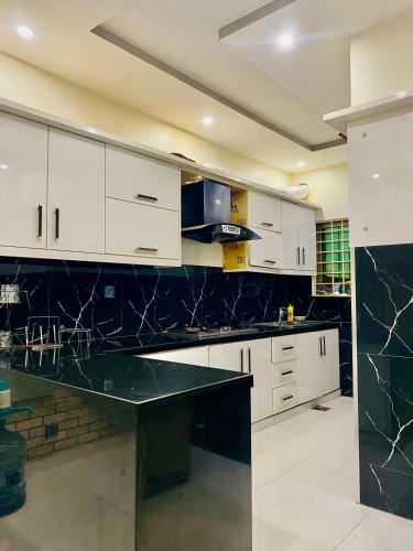 a kitchen with white cabinets and a black counter top at Bahria Oasis in Karachi