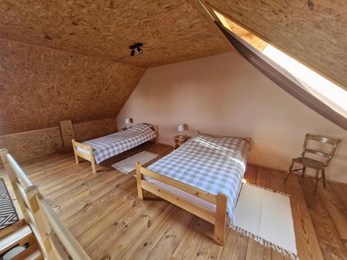 an attic room with two beds and a chair at Żwirowa Góra - Domki nad Narwią in Tykocin