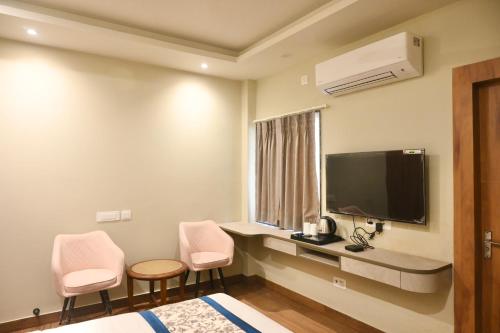 a hotel room with two pink chairs and a tv at Galaxy Triveni in Prayagraj