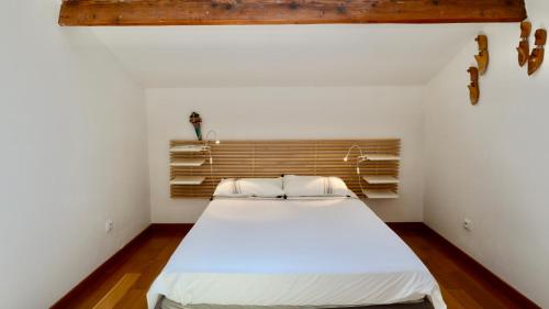 une chambre avec un lit blanc avec une tête de lit en bois dans l'établissement Maison de vacances proche plage de la Bergerie, à Hyères