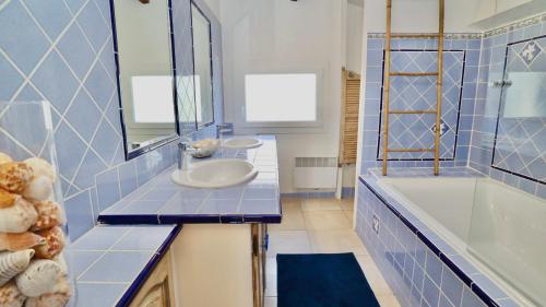 une salle de bain carrelée bleue avec un lavabo et une baignoire dans l'établissement Maison de vacances proche plage de la Bergerie, à Hyères