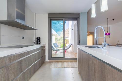 a kitchen with a sink and a door to a patio at Casa Azahar playa Cabo De Gata 2 in Las Hortichuelas Bajas