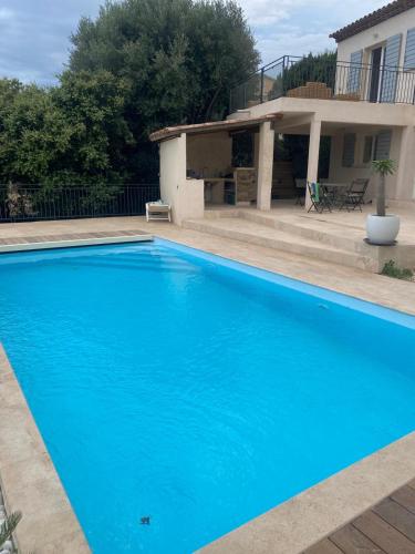 une grande piscine bleue devant une maison dans l'établissement villa à bormes les mimosas, à Bormes-les-Mimosas
