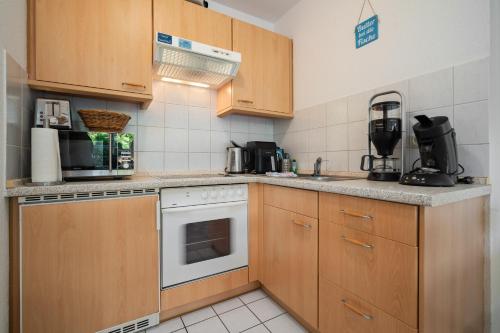 una cucina con armadi in legno e un piano cottura bianco con forno di Leuchtturm a Stakendorfer Strand