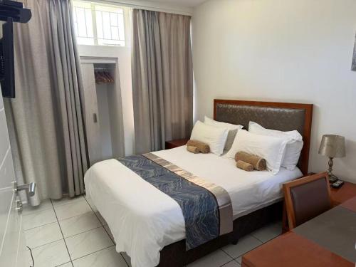 a hotel room with a bed with two stuffed animals on it at Home Inn Self-Catering in Windhoek