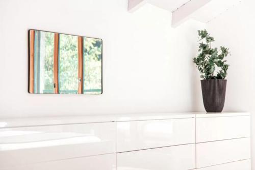 a white room with a mirror and a plant on a dresser at Mansarda Gentilino by Quokka 360 - Charming attic retreat in nature in Collina d'Oro