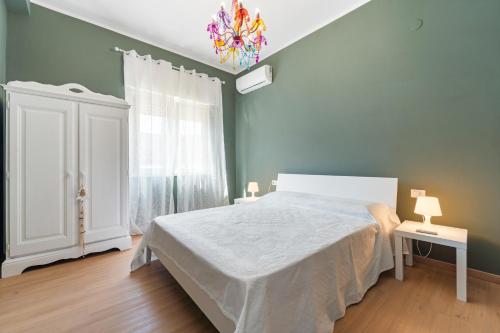 サンタンティーオコにあるCasa di Pinaの白いベッドとシャンデリアのある寝室