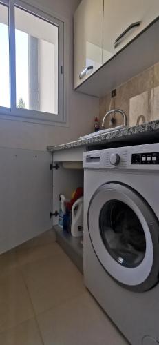 a washing machine in a kitchen with a sink at ConfortTek apartment in Boumhel El Bassatine