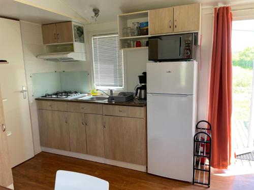 une cuisine avec un réfrigérateur blanc et un évier dans l'établissement Camping Seasonova Ensoya, à Sigean