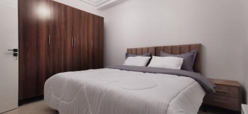 a bedroom with a large bed with a wooden cabinet at ConfortTek apartment in Boumhel El Bassatine