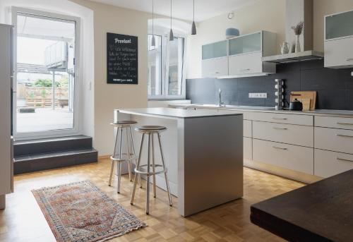 a kitchen with white cabinets and bar stools at Boardinghouse siebzehn82 in Endingen